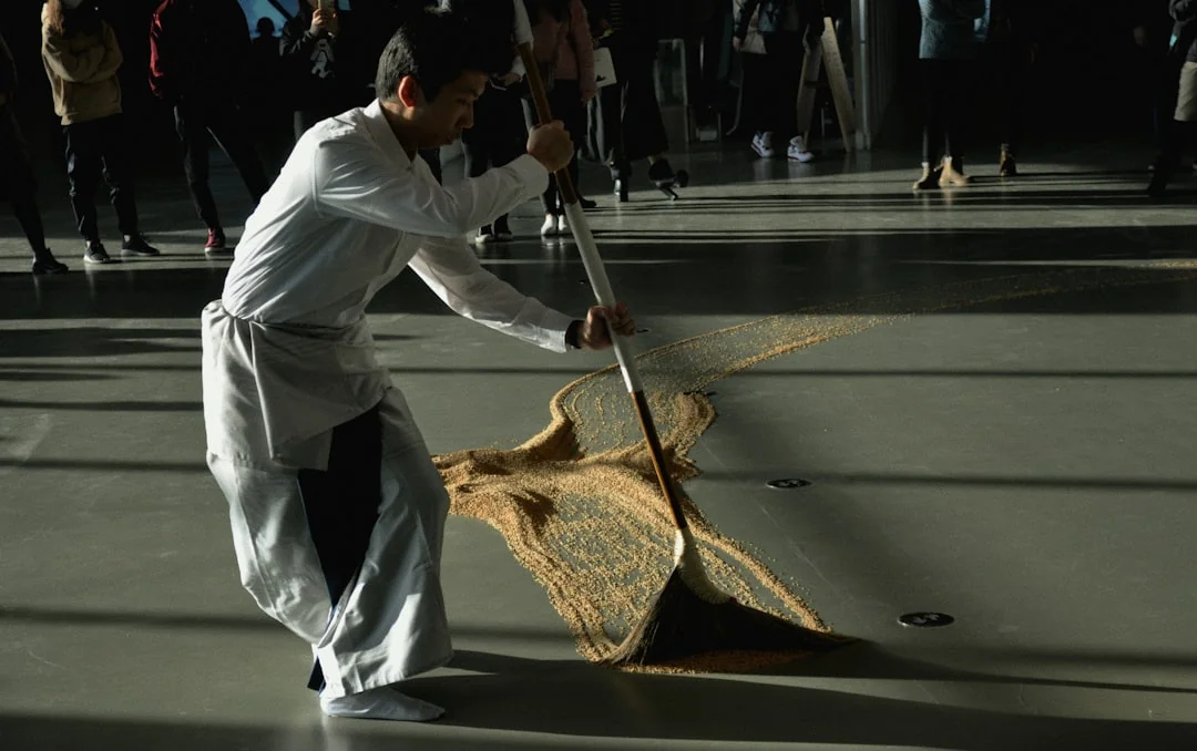 An adult woman wearing red coveralls is using a vacuum cleaner in a modern indoor environment, concentrating on cleaning duties.